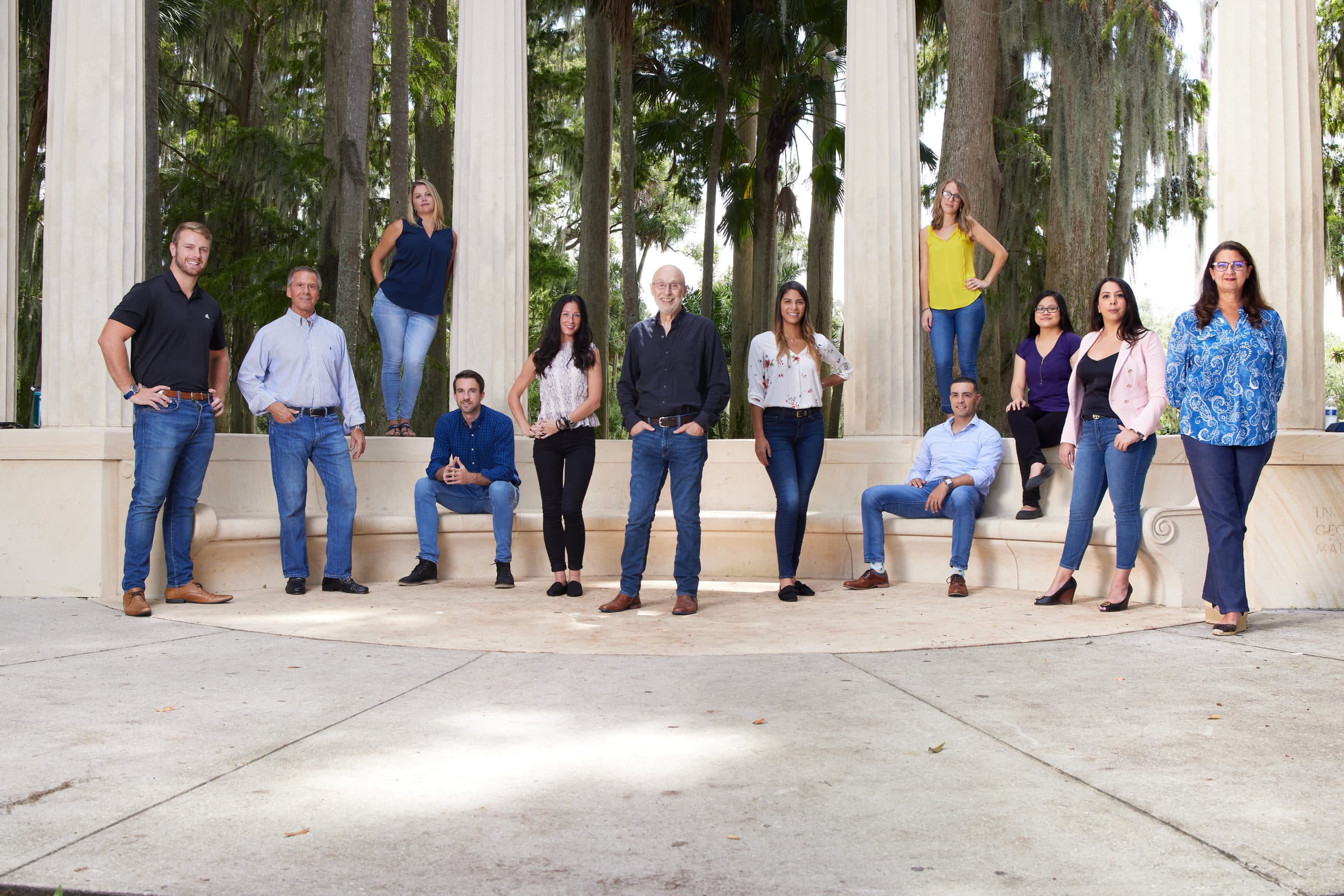Group of professionals posing together at an outdoor columned pavilion.