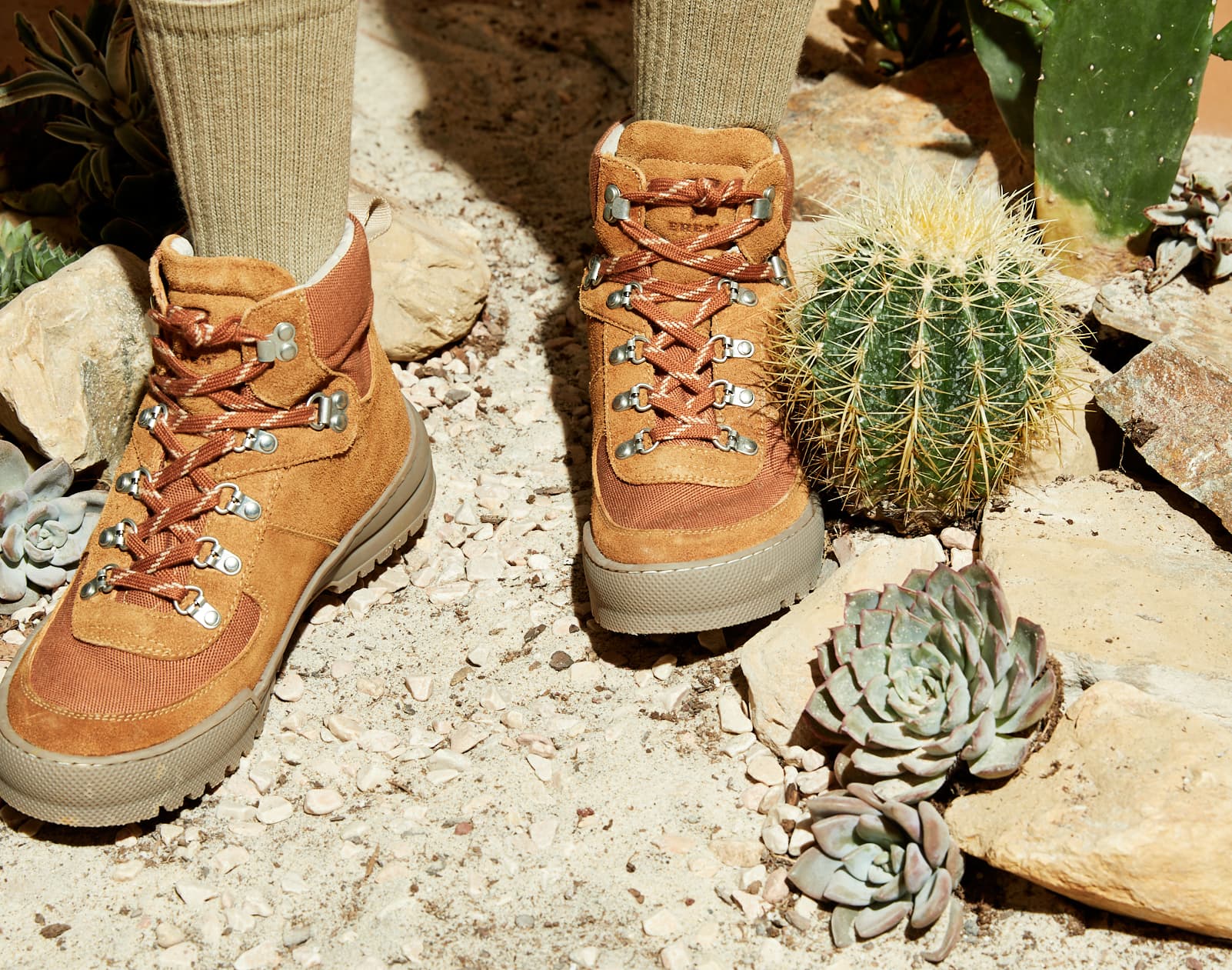 Hiker wearing tan suede boots standing among cacti and succulents