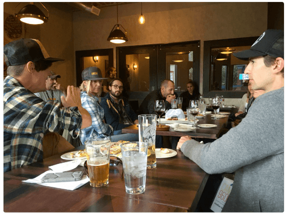Group of people seated around a table with drinks in conversation