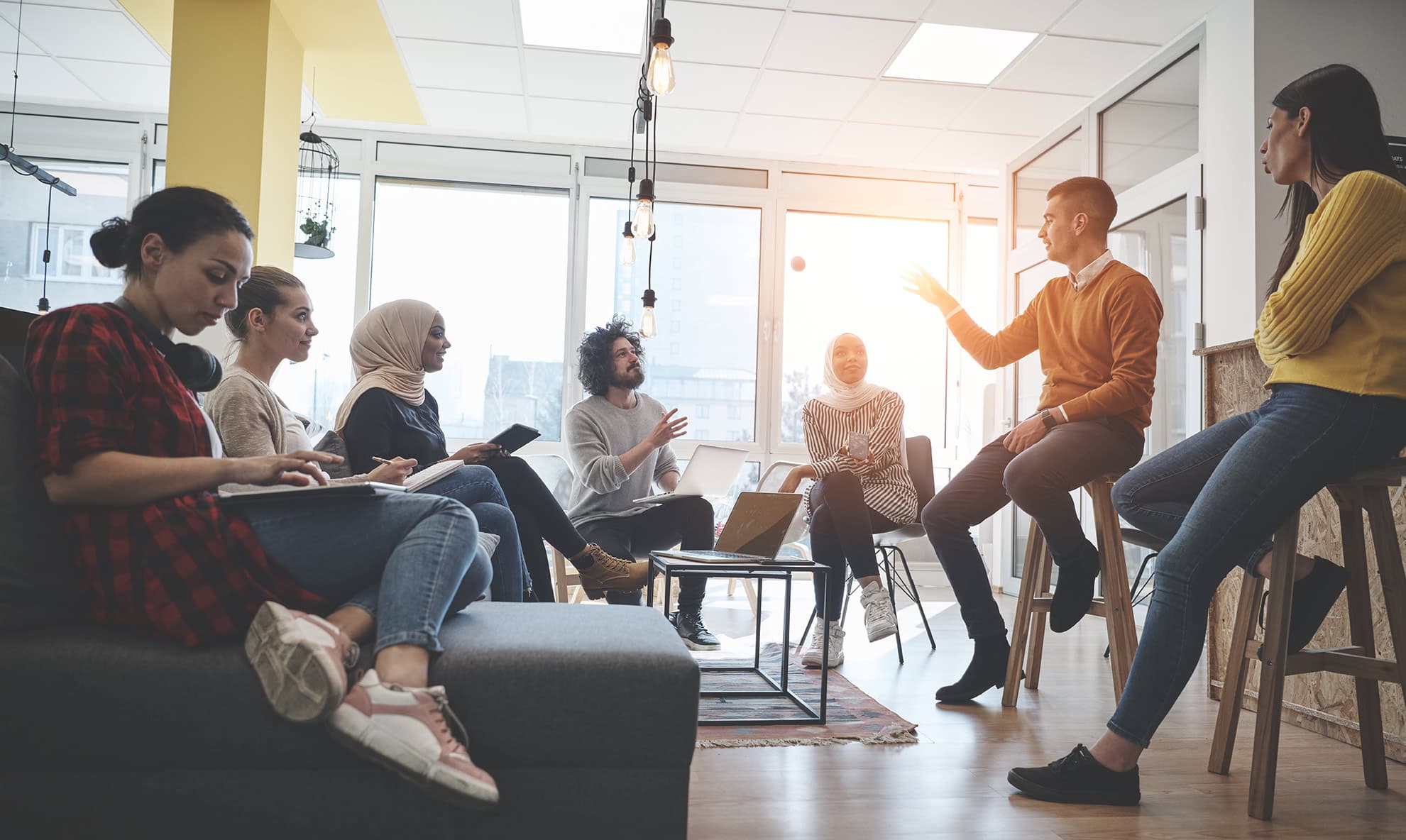 Team of coworkers meeting casually in a bright modern office space.