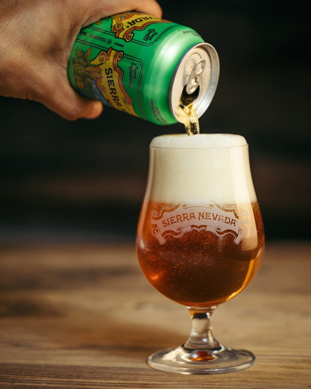 Hand pouring Sierra Nevada beer from a can into a branded glass.