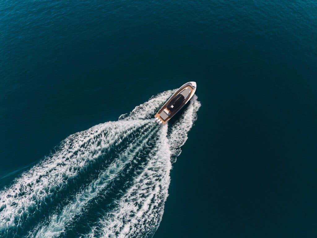 Aerial view of a Revel yacht cutting through open water leaving a white wake