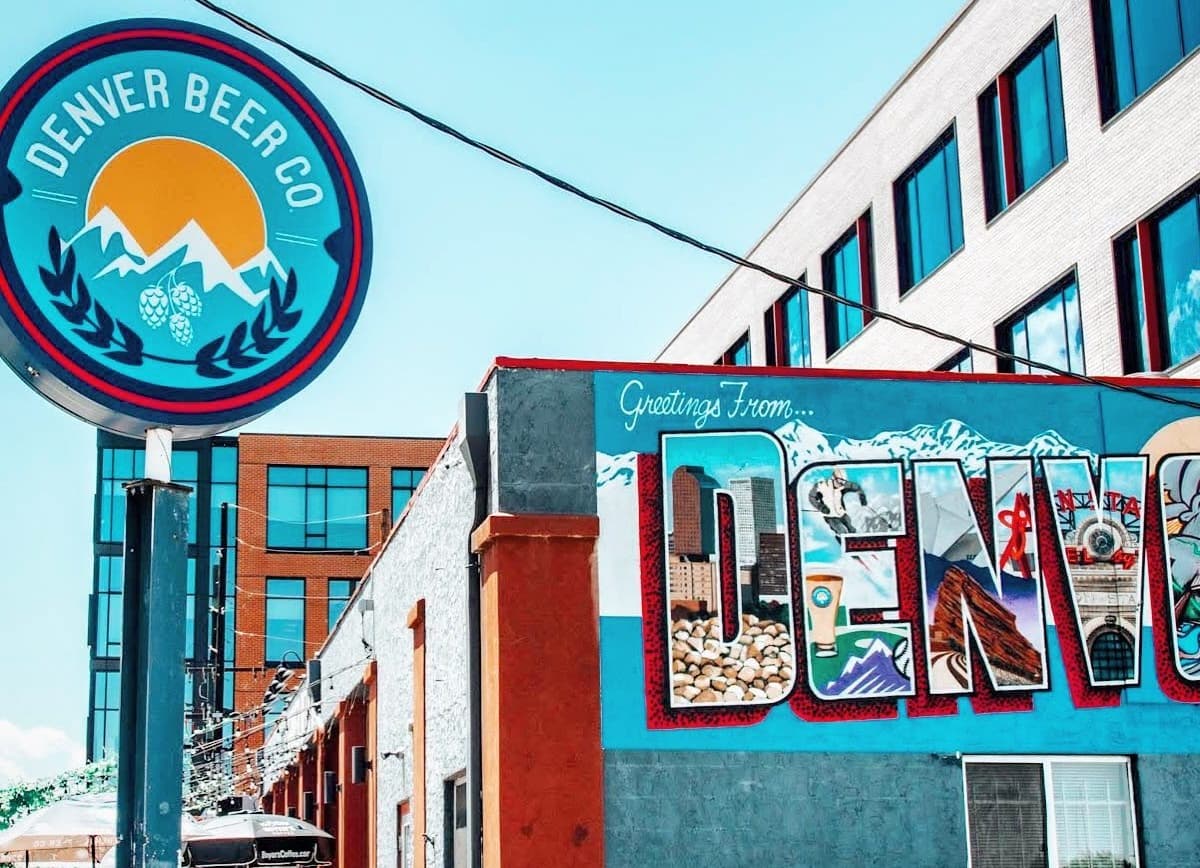 Denver Beer Co sign beside a colorful 'Greetings From Denver' mural