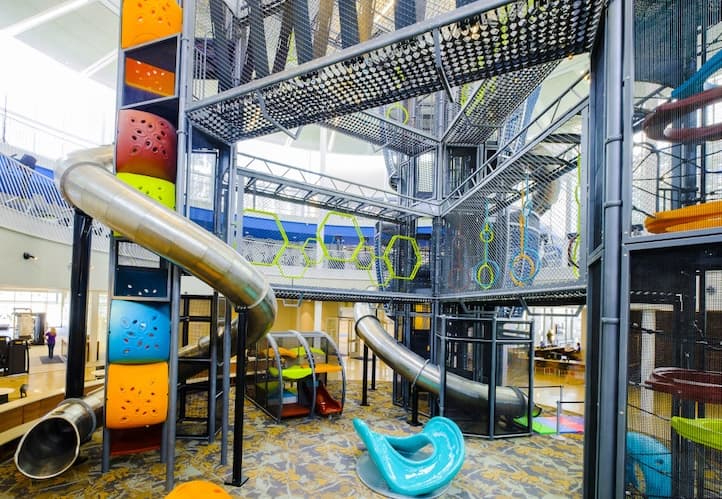 Multi-level indoor play structure with spiral slides, climbing nets, and colorful towers